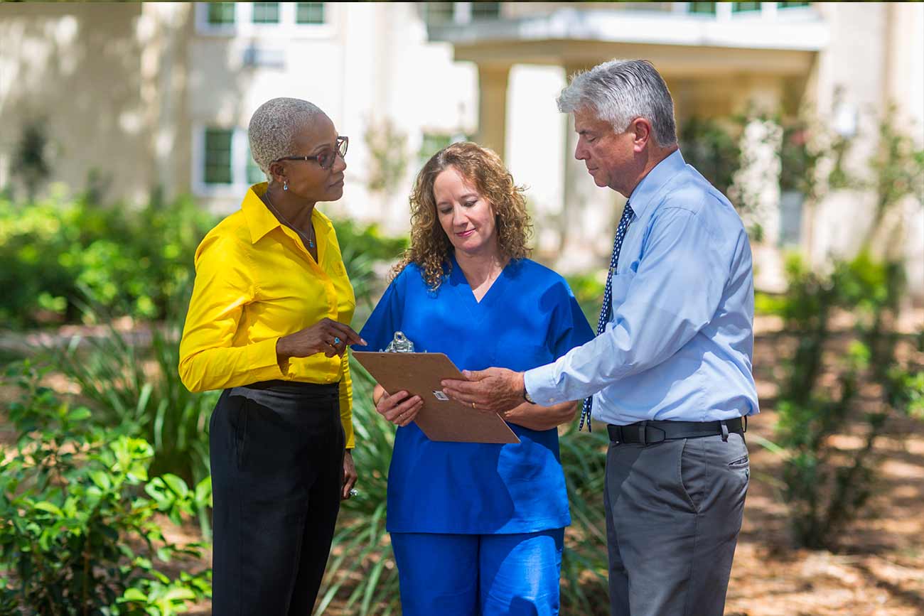 three people standing outside looking at medical clipboard