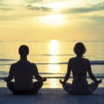 holistic couple meditating while doing yoga