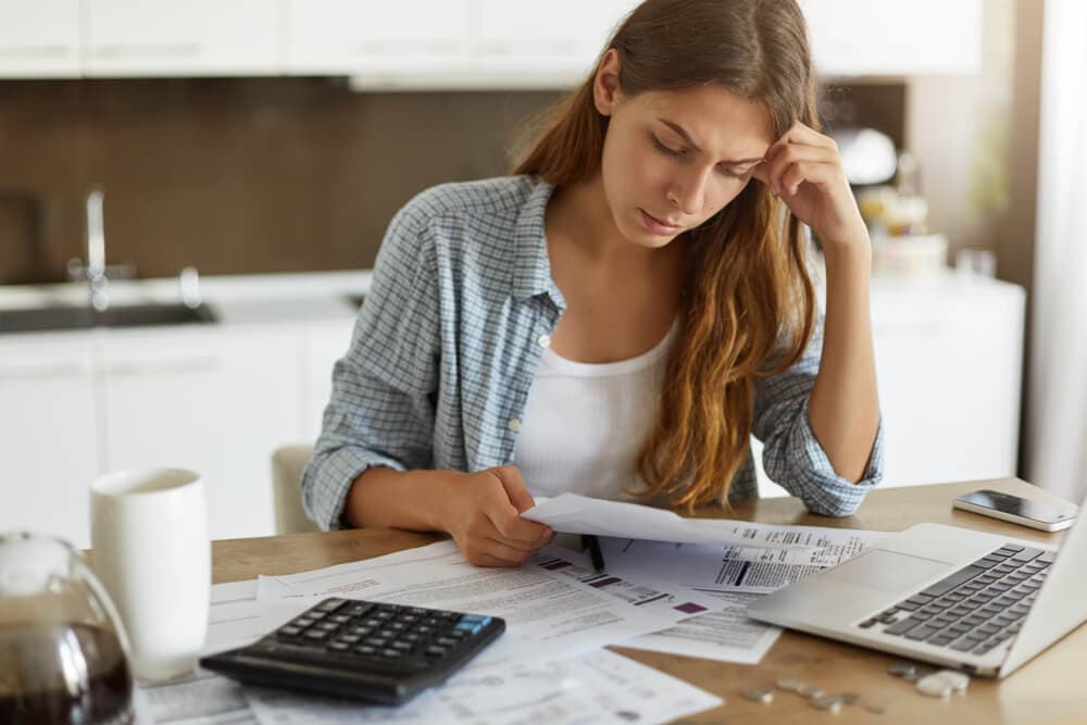 woman looking at paperwork next to a computer and calculator