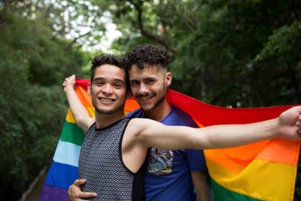 Two men hugging and holding a pride flag
