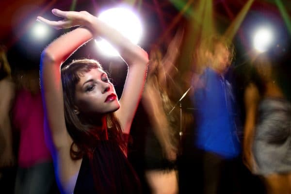 female at dance club with arms above head