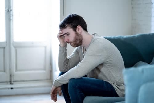 worried man sitting on couch with head in his hand