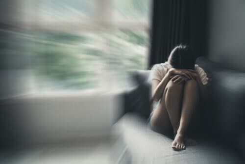 woman sitting on a couch with head down and blurred background