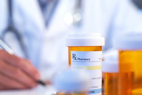 prescription pill bottles with doctor writing prescriptions